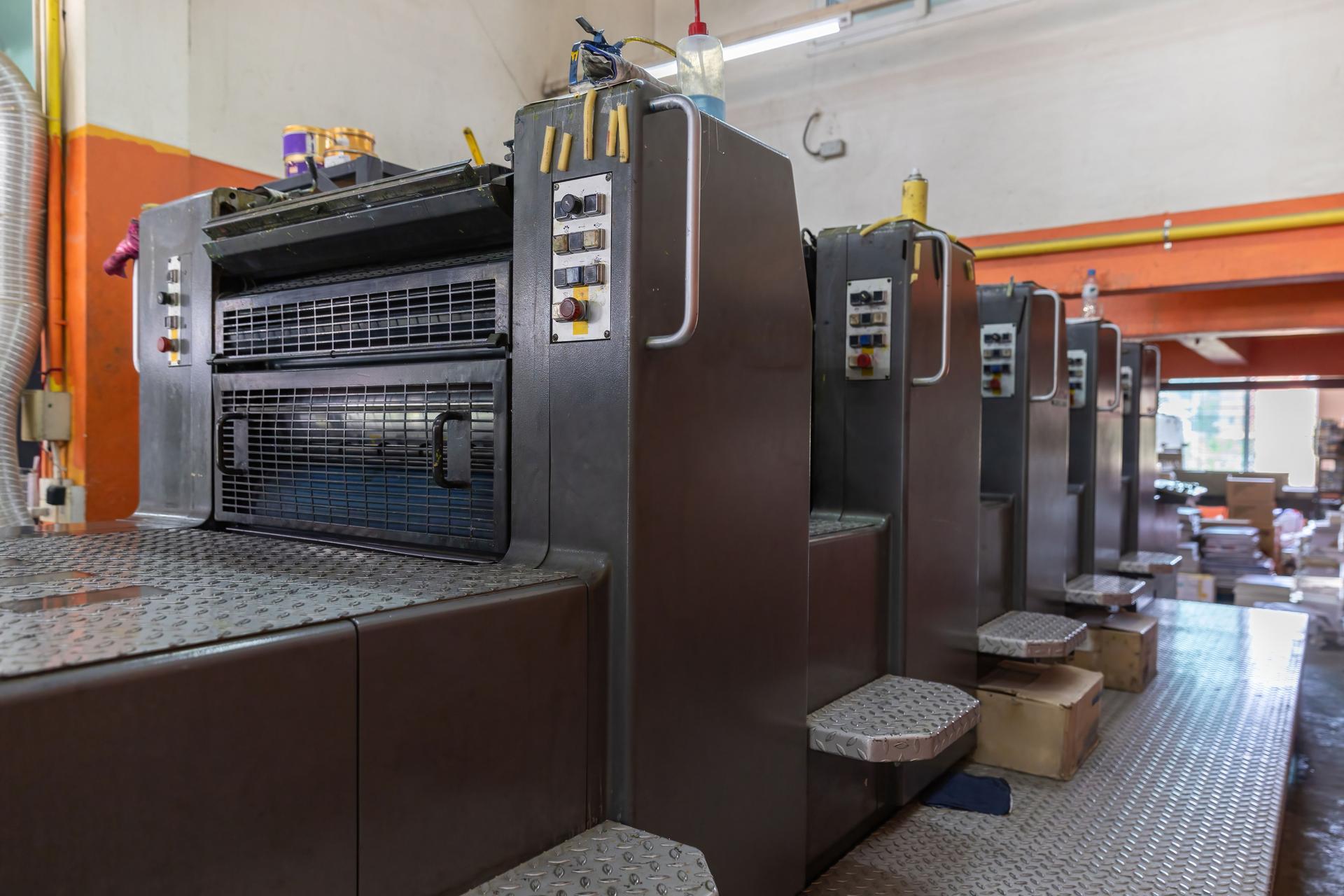 Offset printing machines. Large printing machine perspective. printing machine cylinders and printing ink pot. Offset machine. Offset press is a printing machine designed to produce fine quality